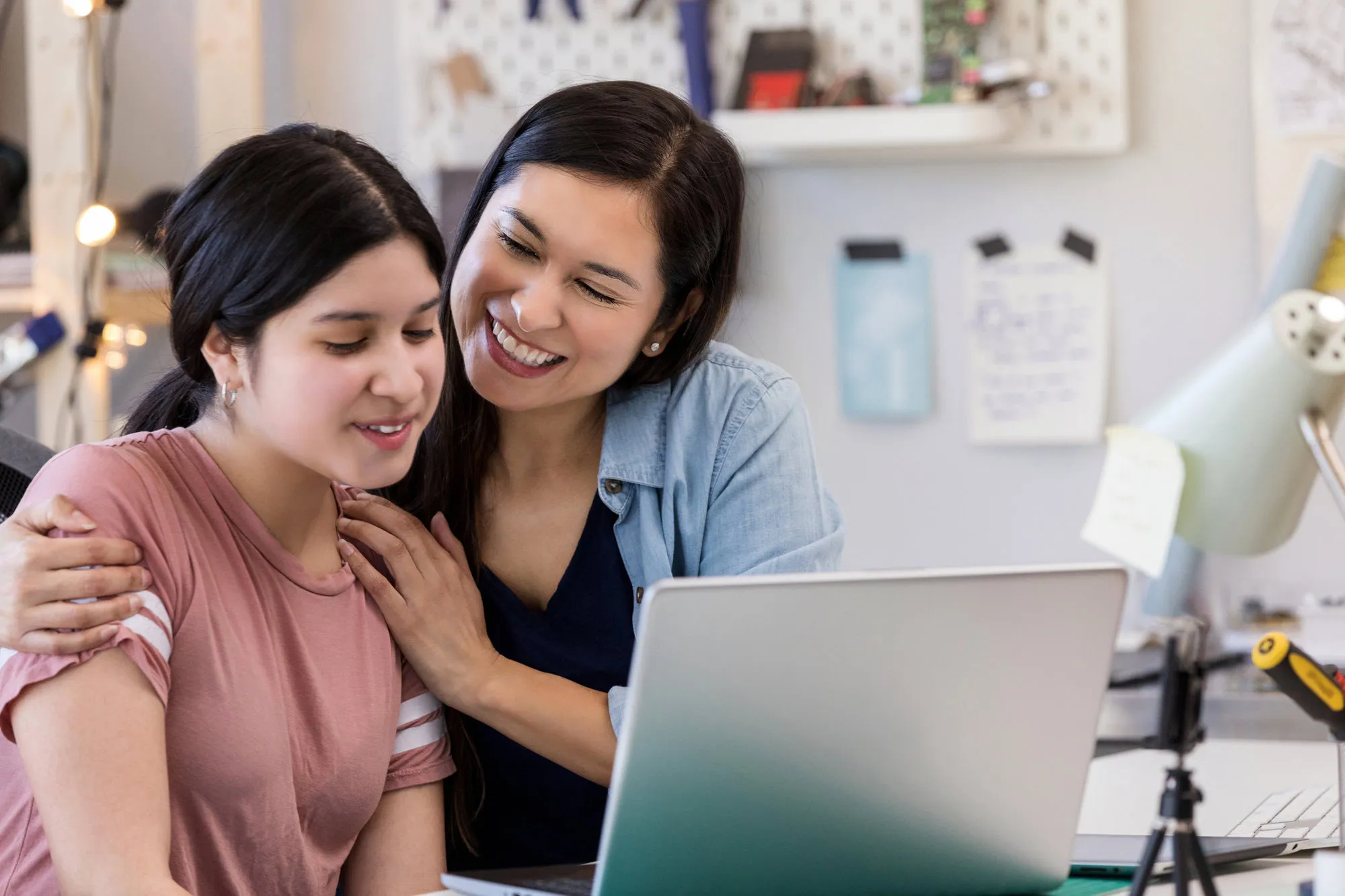 Mother hugs daughter after seeing her good work on laptop